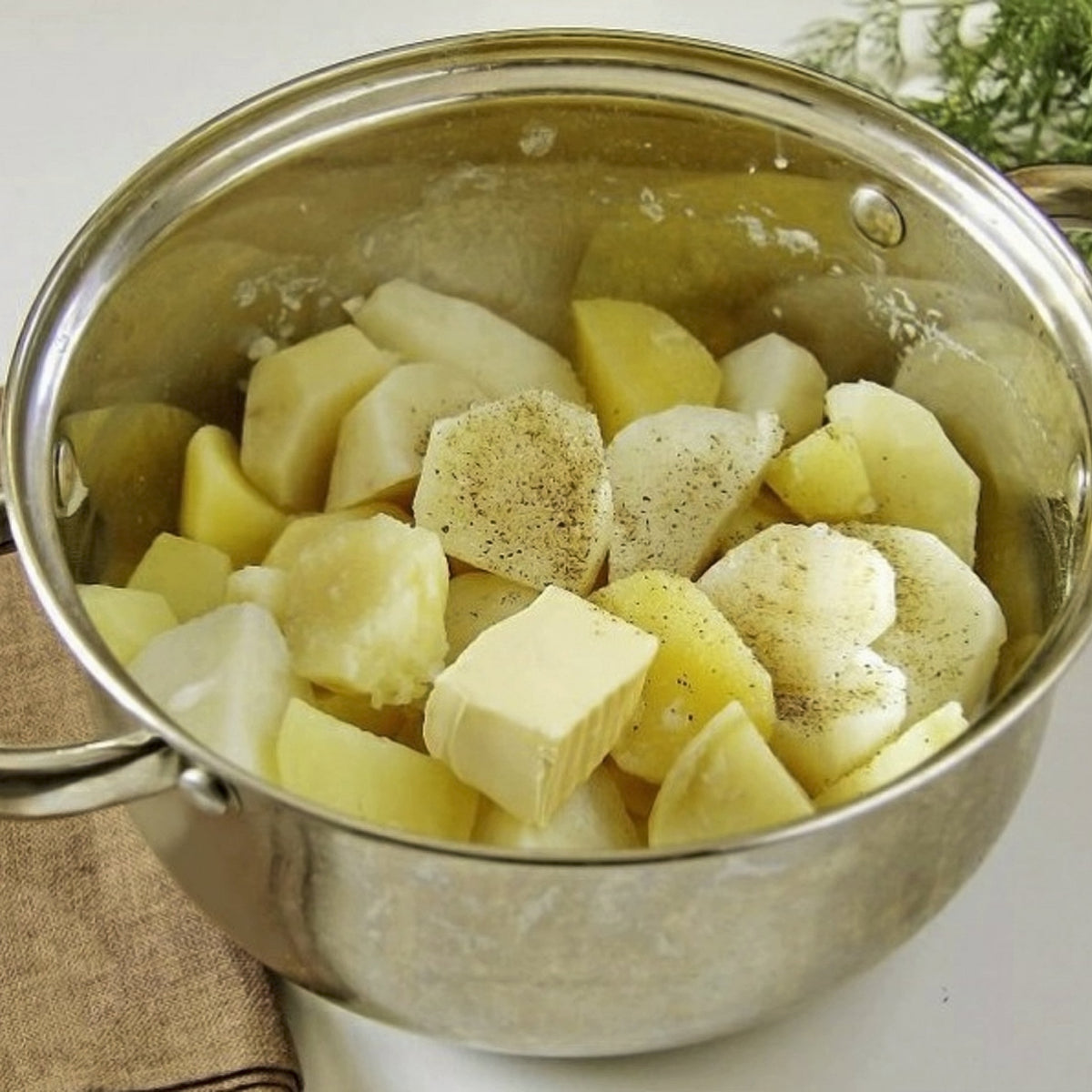 Chopped potatoes sit in a saucepan of water, showing Australian Cooking Salt Fine used when seasoning potatoes during cooking.