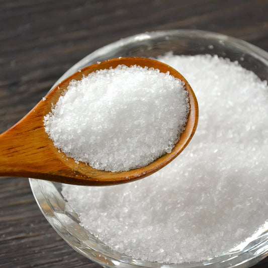 Fine Australian Cooking Salt fills a wooden spoon resting over a bowl of salt, showing its fine white crystalline texture.