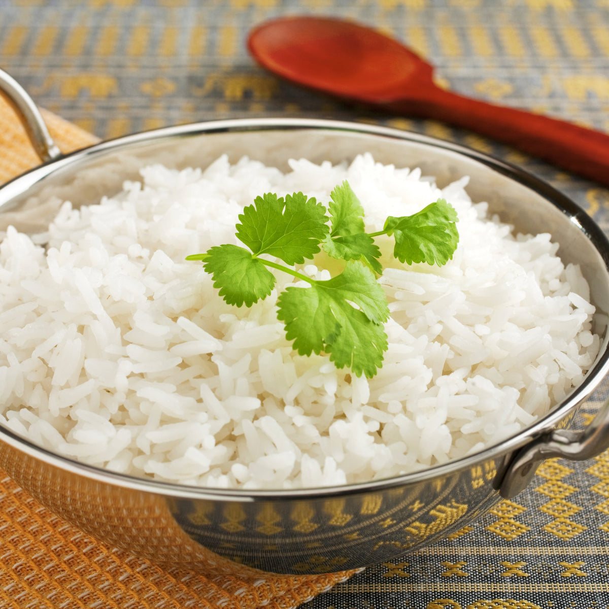 A bowl of fluffy cooked Basmati Rice Long Grain garnished with fresh coriander, showing the separate, elongated grains after cooking.