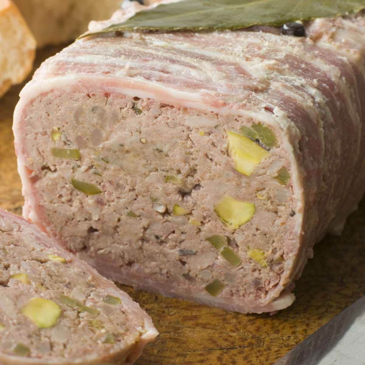 Slices of a savoury meat terrine with visible herbs and pistachios, showing Bay Leaves used as part of a seasoned savoury recipe.