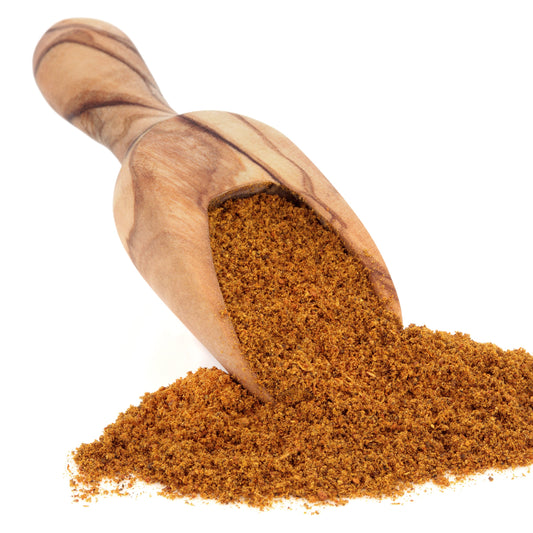 Moroccan Spice Blend from The Herb Shed Wollongong, Australia, spills from a wooden scoop, showing the finely ground spice blend and its warm earthy brown colouring.