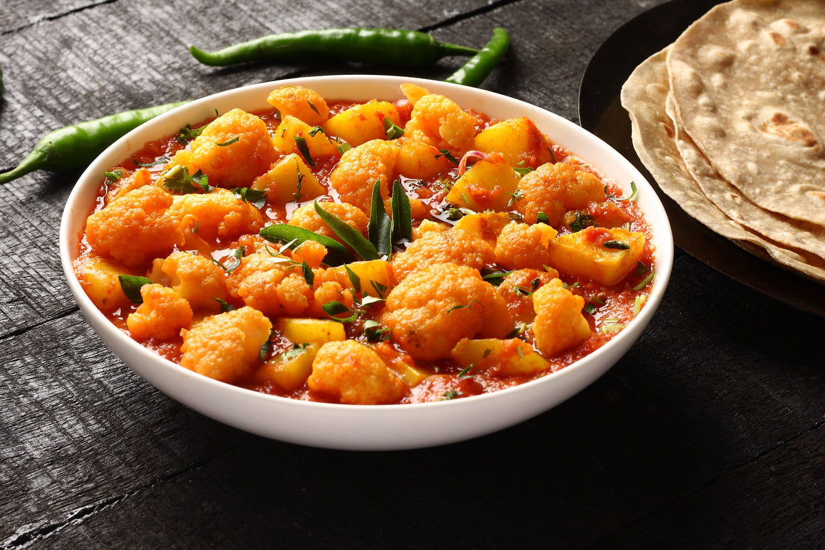 A richly coloured curry served with flatbread, showing Organic Fenugreek from The Herb Shed in Wollongong, Australia, used in a savoury spiced dish.