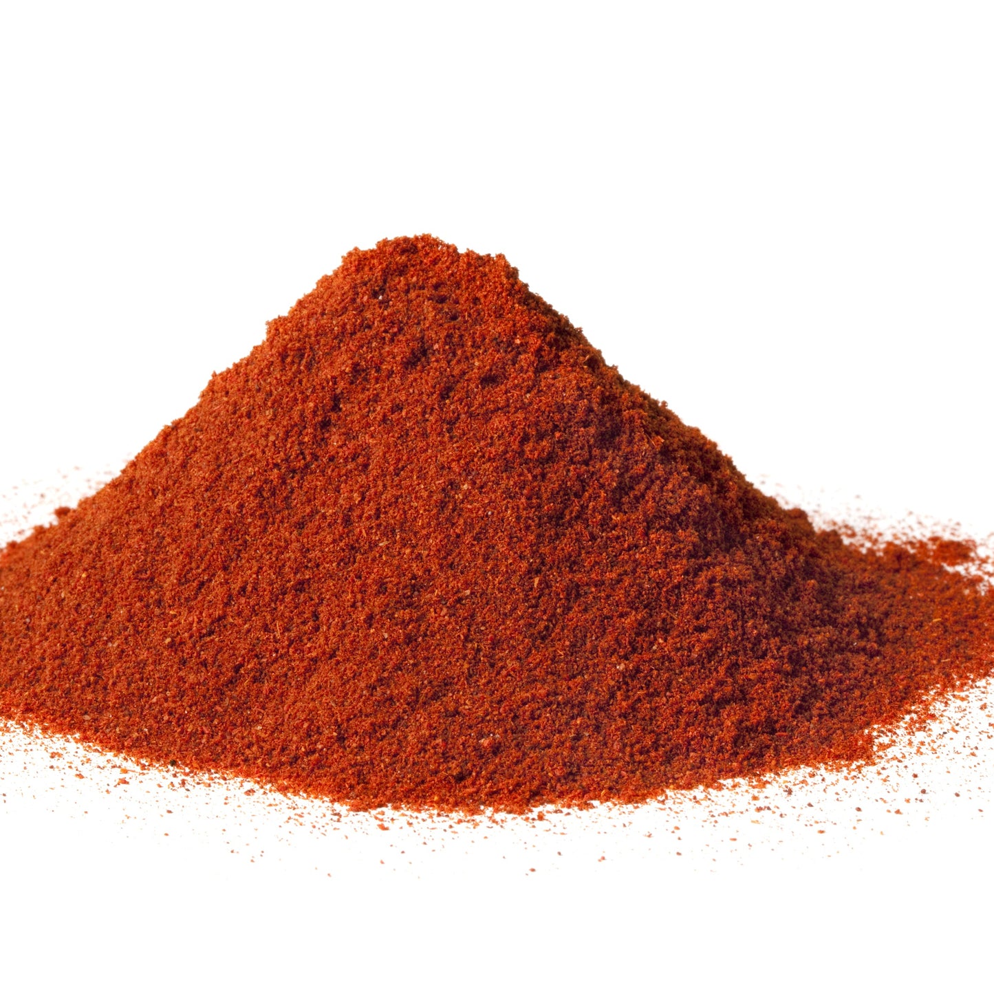 A mound of finely ground hot paprika powder on a white surface shows the spice's vivid deep red colour and fine texture.