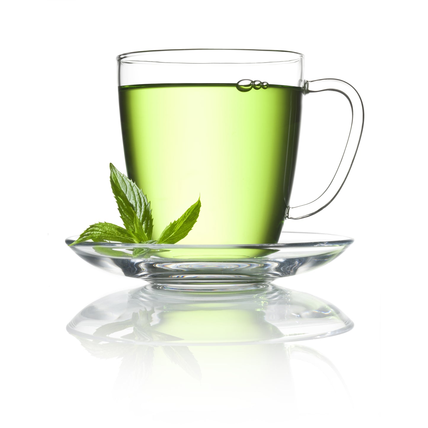 A clear glass cup of green peppermint tea sits on a white saucer with fresh mint leaves beside the cup.
