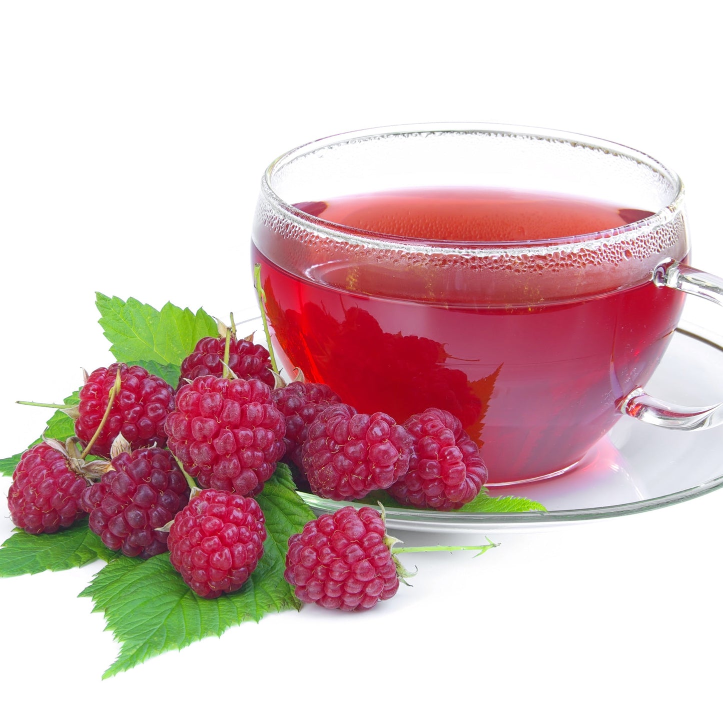 A clear glass cup of red raspberry leaf tea sits on a white surface beside fresh raspberries and green raspberry leaves.