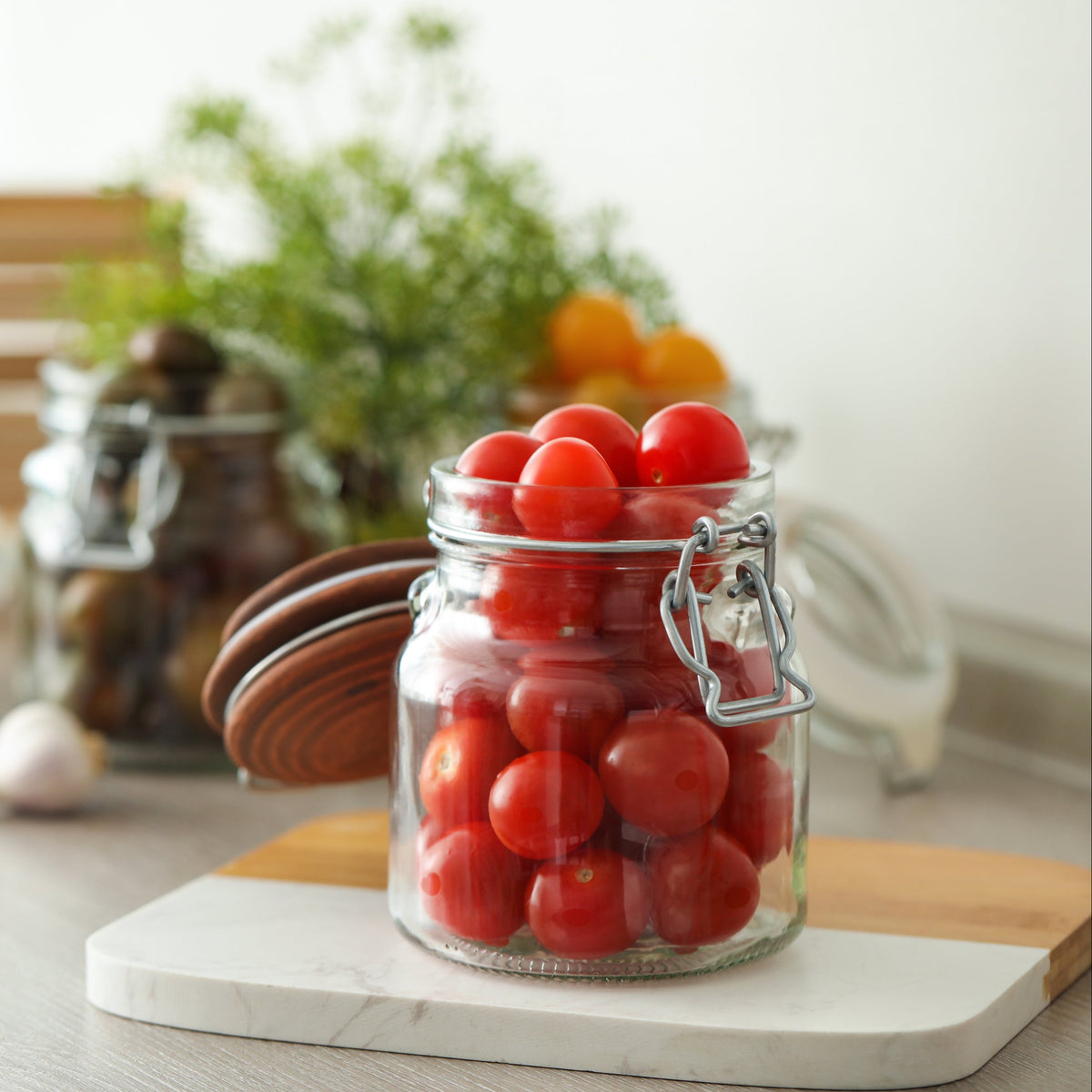 A clip lid glass jar filled with cherry tomatoes on a kitchen bench, showing The Harvest 260ml Jar from The Herb Shed in Wollongong, Australia, used for preserving fresh produce.