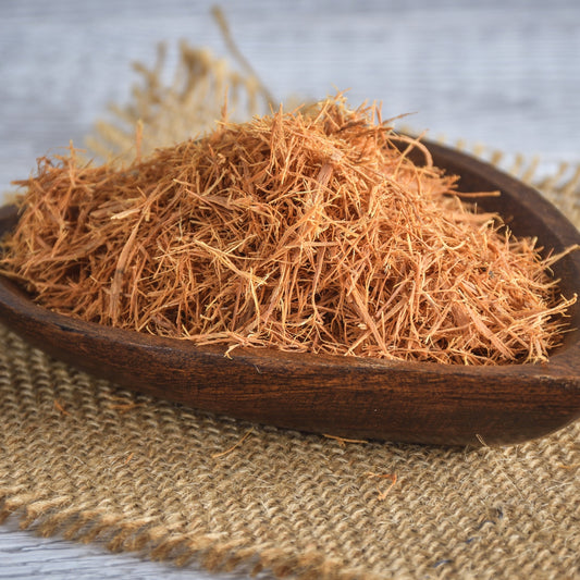 Wildcrafted Cats Claw bark fills a wooden bowl on a natural hessian surface, showing the finely shredded dried bark and its warm reddish-brown colouring and fibrous texture.