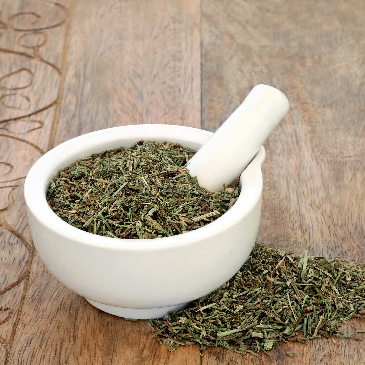 Dried horsetail in a white mortar and pestle sitting on a wooden table – earthy herbal stem from The Herb Shed Wollongong