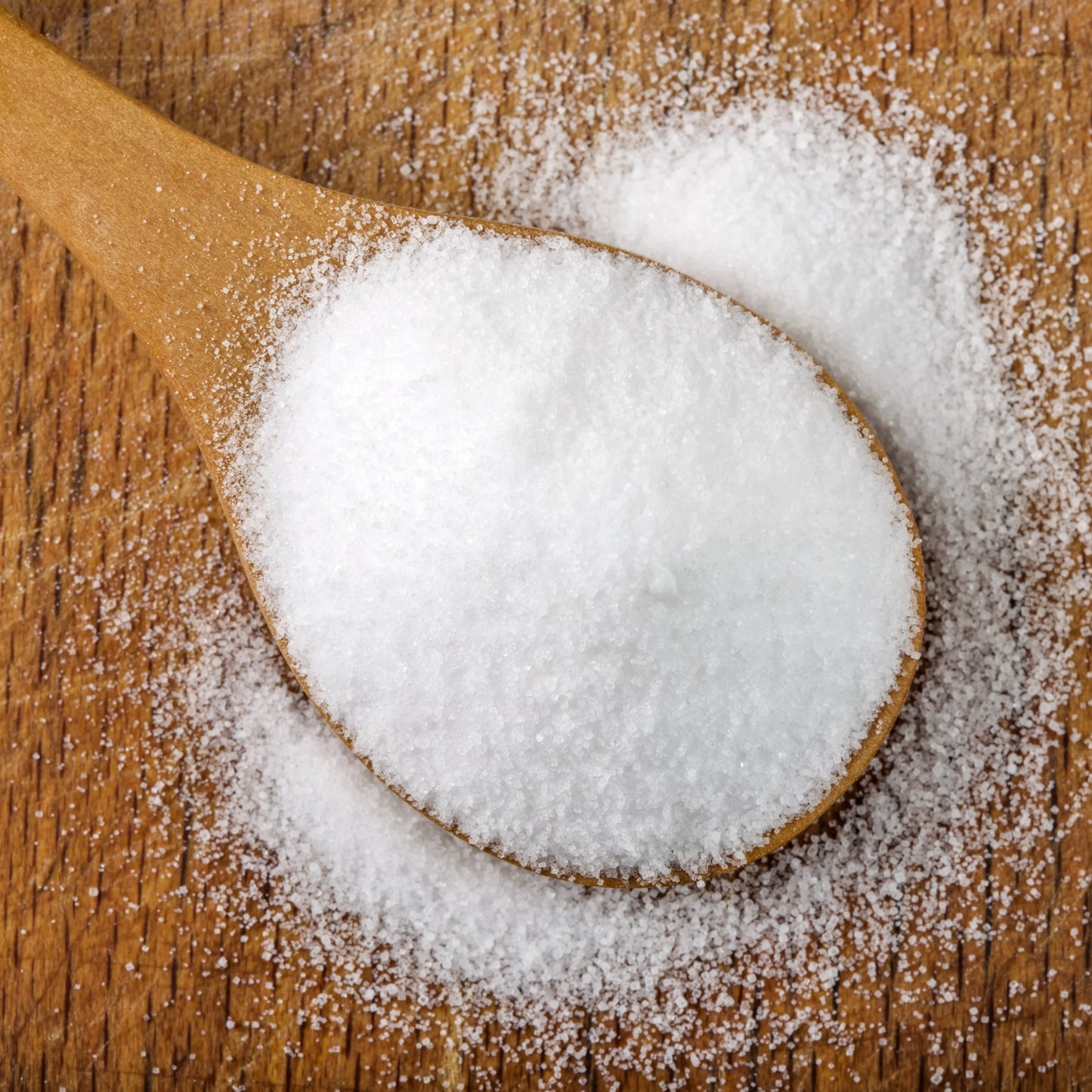 Premium quality pickling salt in wooden spoon on timber surface.