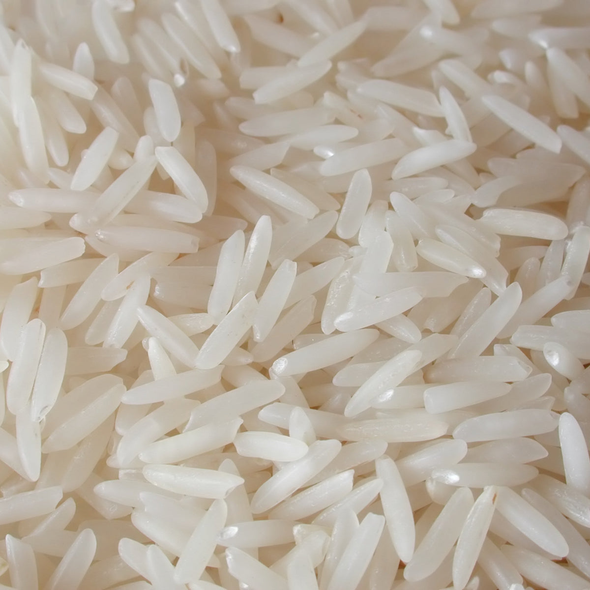 A close-up of uncooked Basmati Rice Long Grain, showing the individual slender white grains and their distinctive elongated shape.