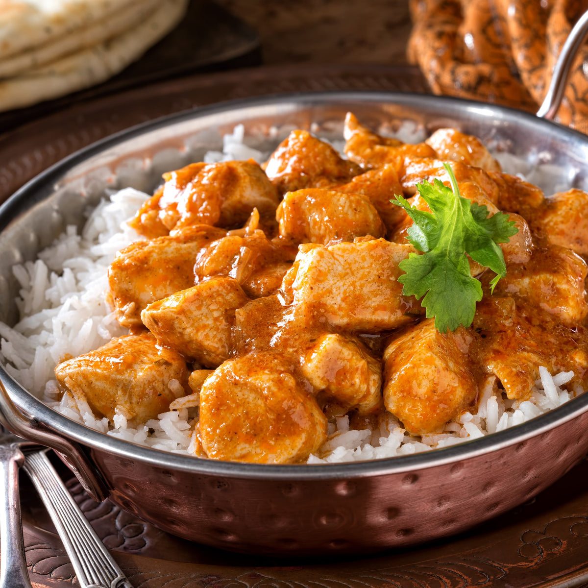 A bowl of fluffy basmati rice topped with a rich curry and fresh coriander, showing Basmati Rice Long Grain served with a savoury curry dish.