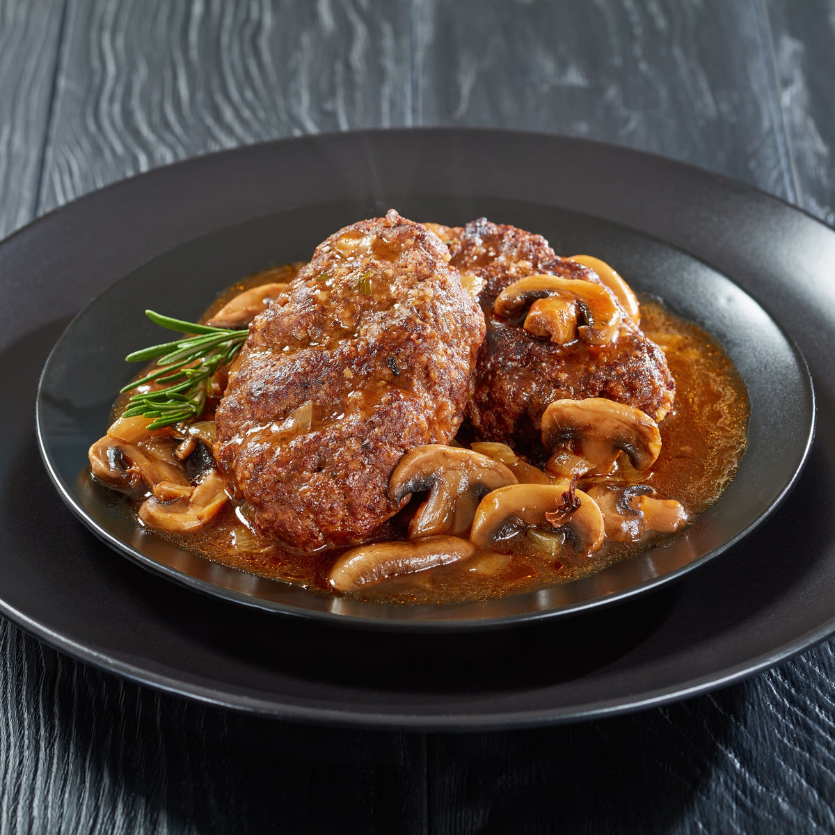 A cooked steak served with mushrooms and sauce is finished with seasoning, showing Black Pepper Ground used with a savoury meat dish.