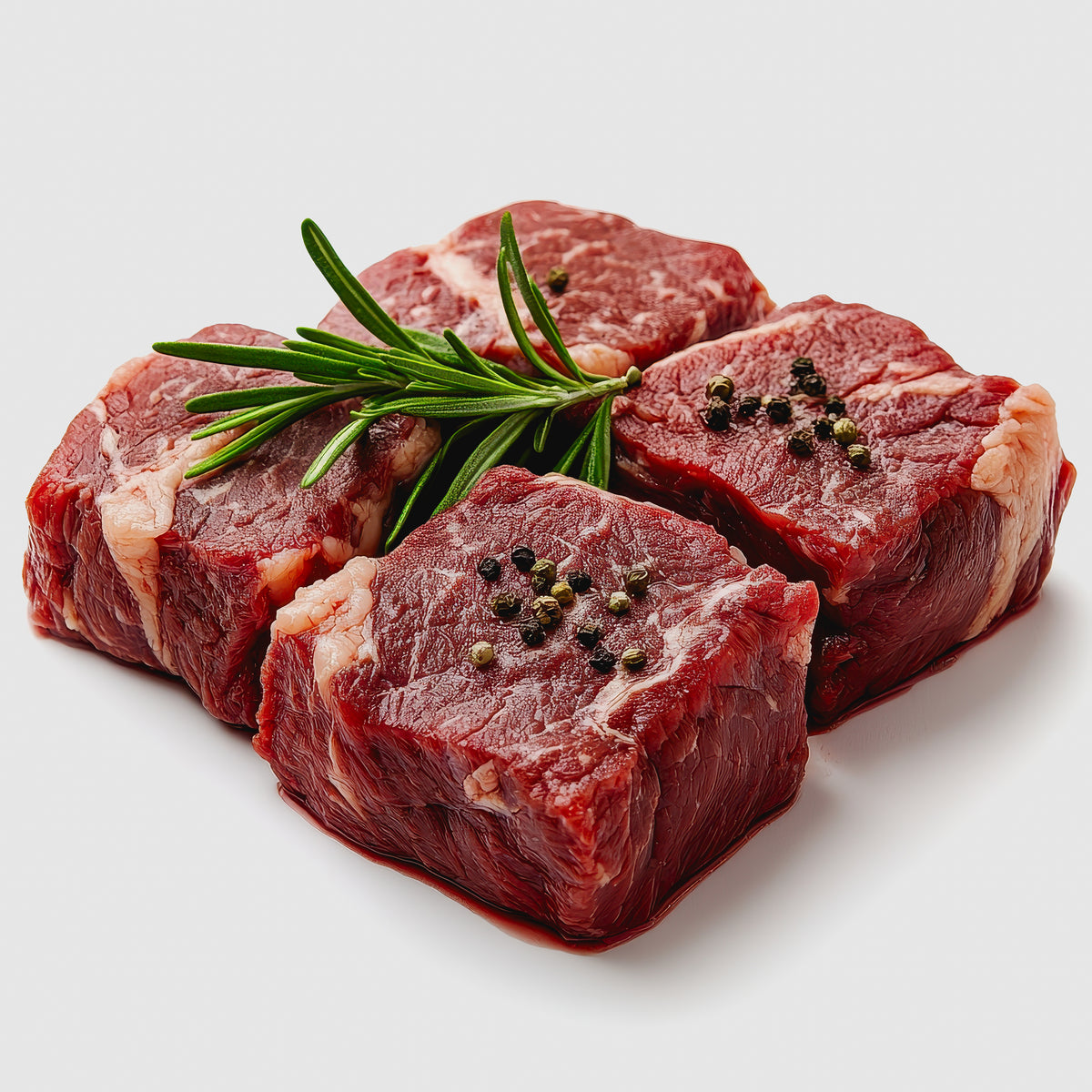 Raw beef steaks are seasoned with whole black peppercorns and fresh rosemary, showing Black Peppercorns used to season meat before cooking.