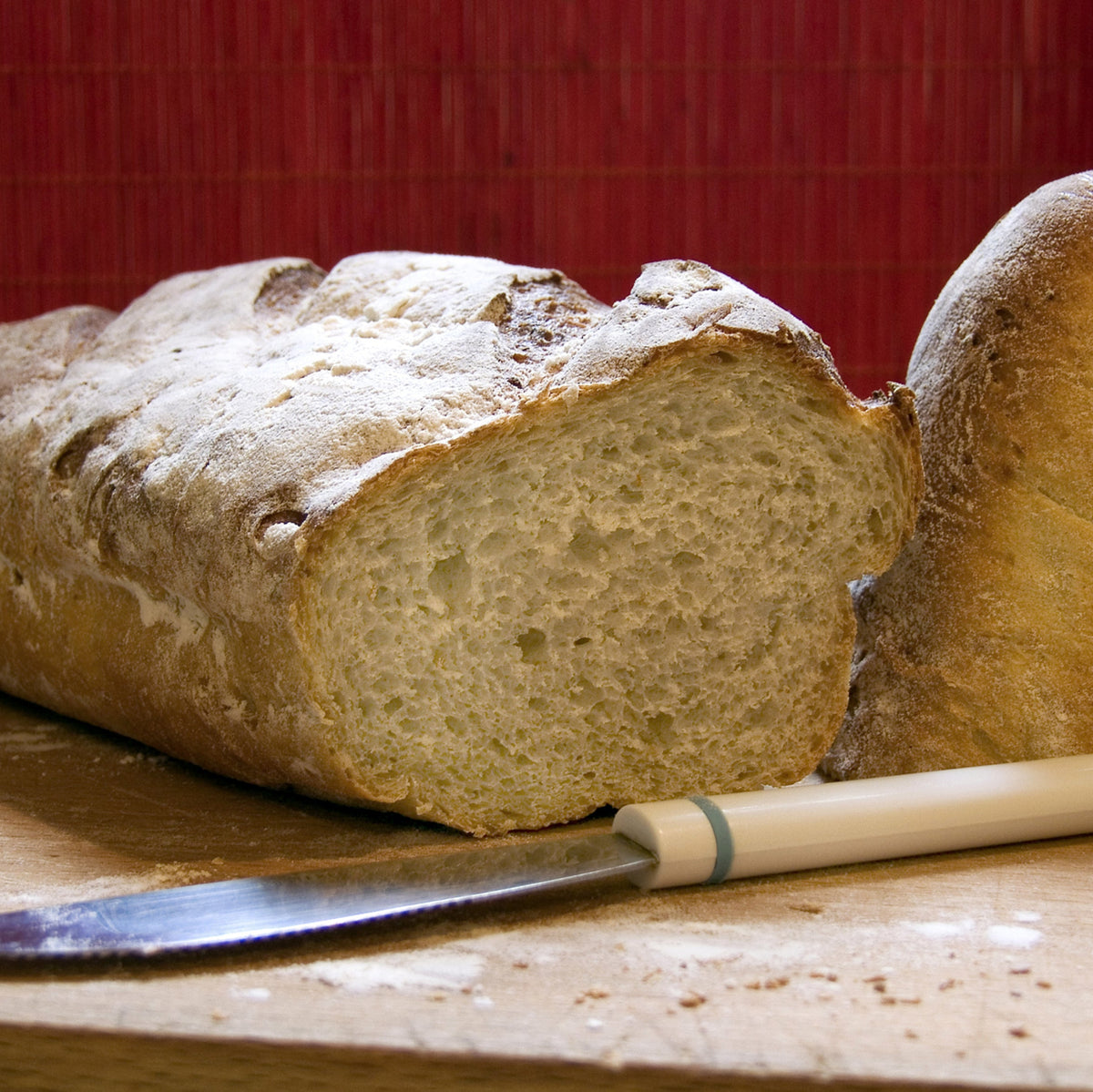 A freshly baked loaf of buckwheat bread dusted with flour and partially sliced, showing Buckwheat Flour used in home baking.