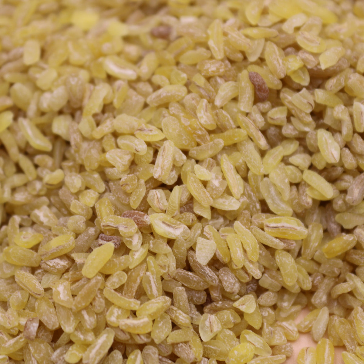 A detailed close-up of fine burghul grains showing their irregular shapes, cracked texture and natural golden-beige colour, from The Herb Shed Wollongong Australia.