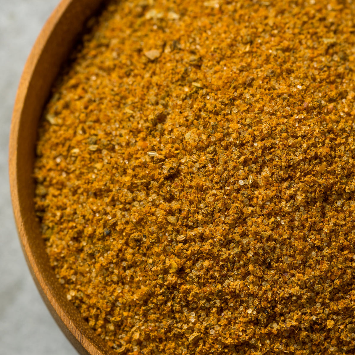 A close-up of Cajun Spice Hand Blended, showing the finely ground seasoning and its warm orange-brown colour with visible flecks of herbs and spices.