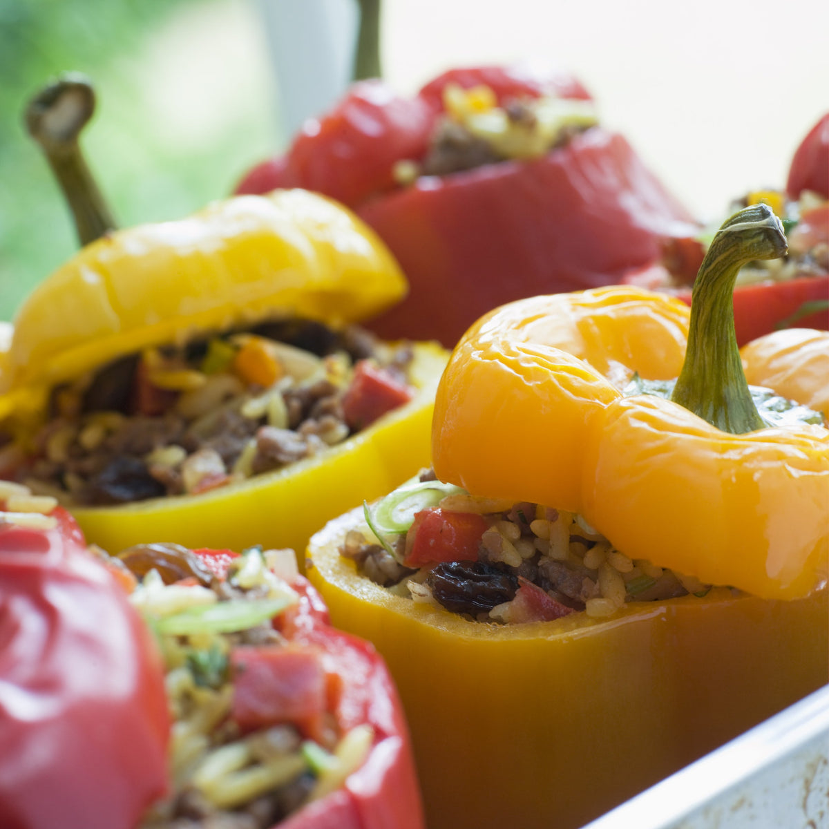 Colourful stuffed capsicums filled with a savoury mixture and topped with herbs, showing Capsicum Confetti Flakes Dried used in a prepared vegetable dish.