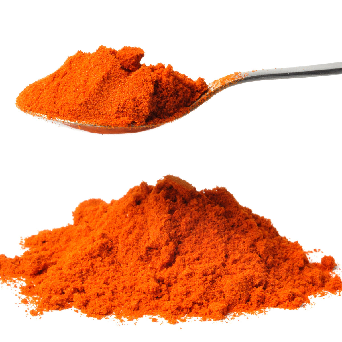 Bright red-orange Cayenne Pepper is piled beneath a spoonful of the ground spice against a white background, showing its fine powdery texture.