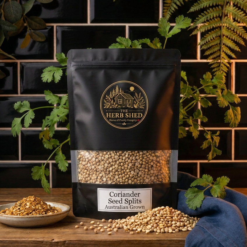 A black stand-up pouch of The Herb Shed Coriander Seeds Whole on a wooden surface, surrounded by greenery with whole coriander seeds displayed in front.