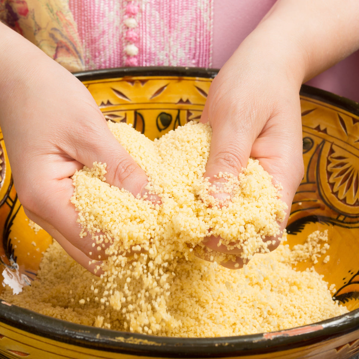 Couscous being prepared by hand in a traditional decorative bowl, showing the fine golden grains, from The Herb Shed Wollongong Australia.