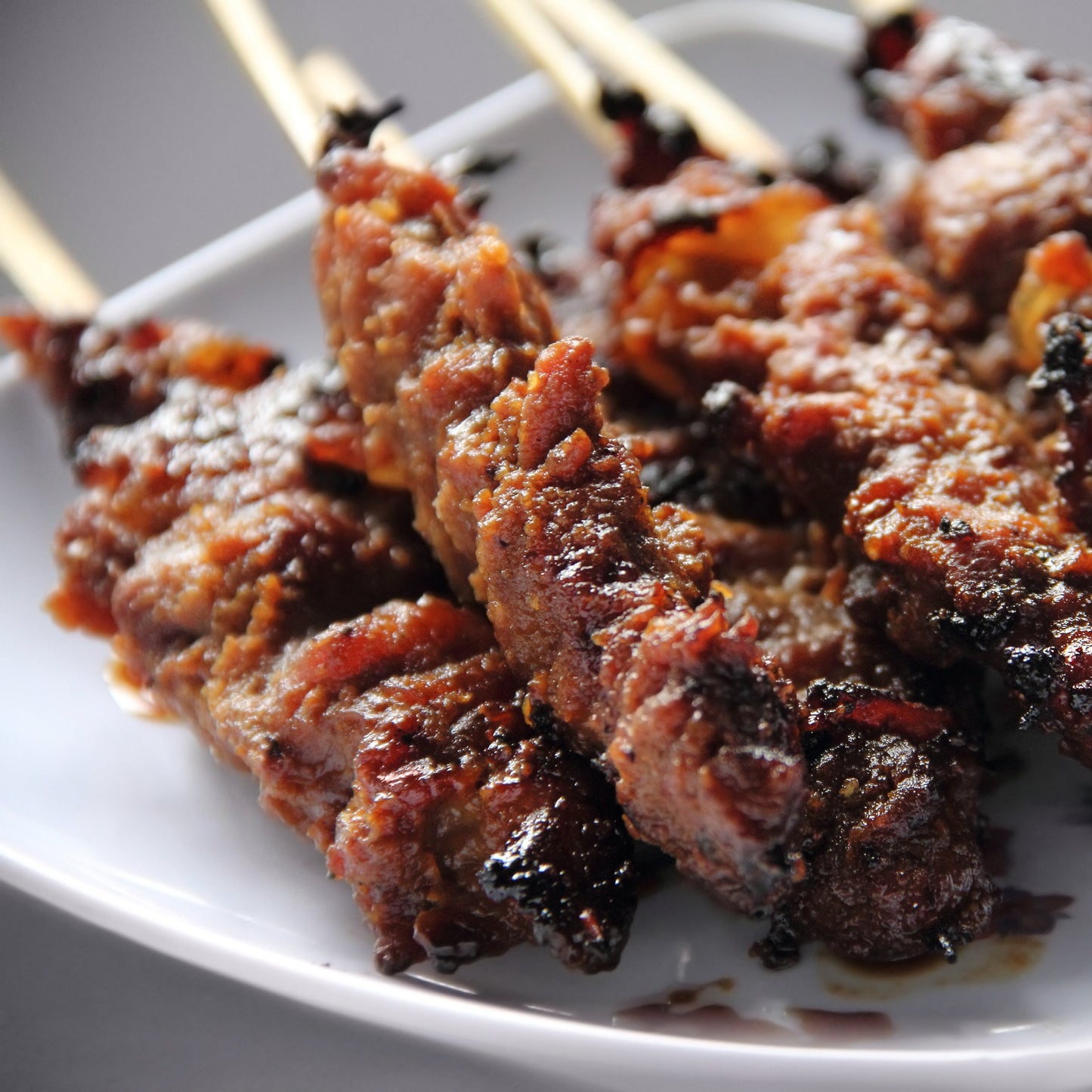 Grilled meat skewers seasoned with garlic and spices are served on a white plate, showing a savoury cooking use for The Herb Shed Garlic Powder.