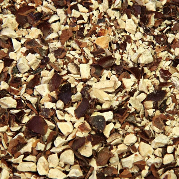 A close-up of chopped dried horse chestnut pieces showing their coarse texture and natural cream, tan and reddish-brown colouring.