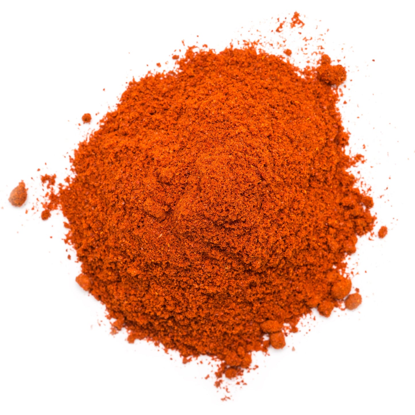 A mound of finely ground Kashmiri chilli powder sits against a white background, showing its fine texture and vivid red-orange colour.