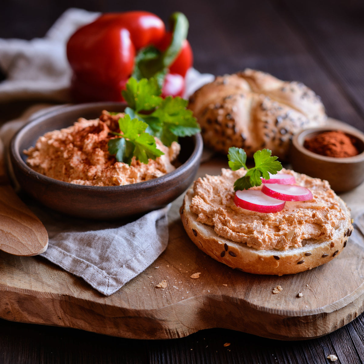Onion powder and other seasonings are arranged with fresh vegetables and prepared food on a rustic wooden surface, showing a savoury cooking use for onion powder.