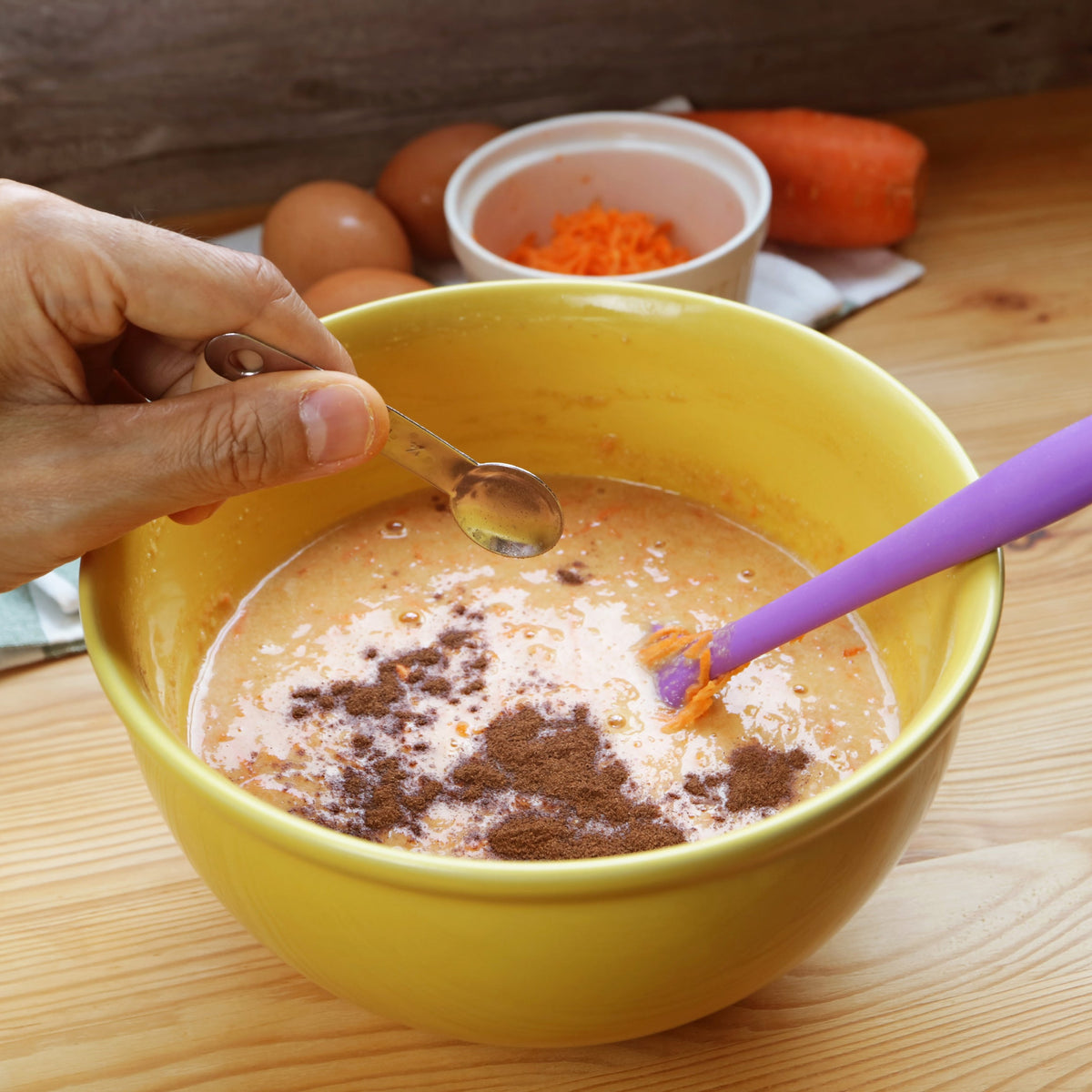 Ground Organic Allspice is added to a bowl of baking mixture beside eggs and other ingredients, showing the spice being used in home baking.