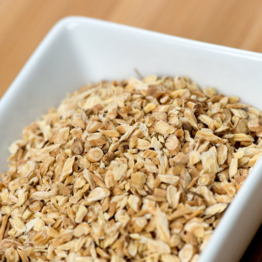 A close-up of Organic Astragalus Root pieces in a white dish, showing the chopped dried root and its natural pale beige colouring and fibrous texture.