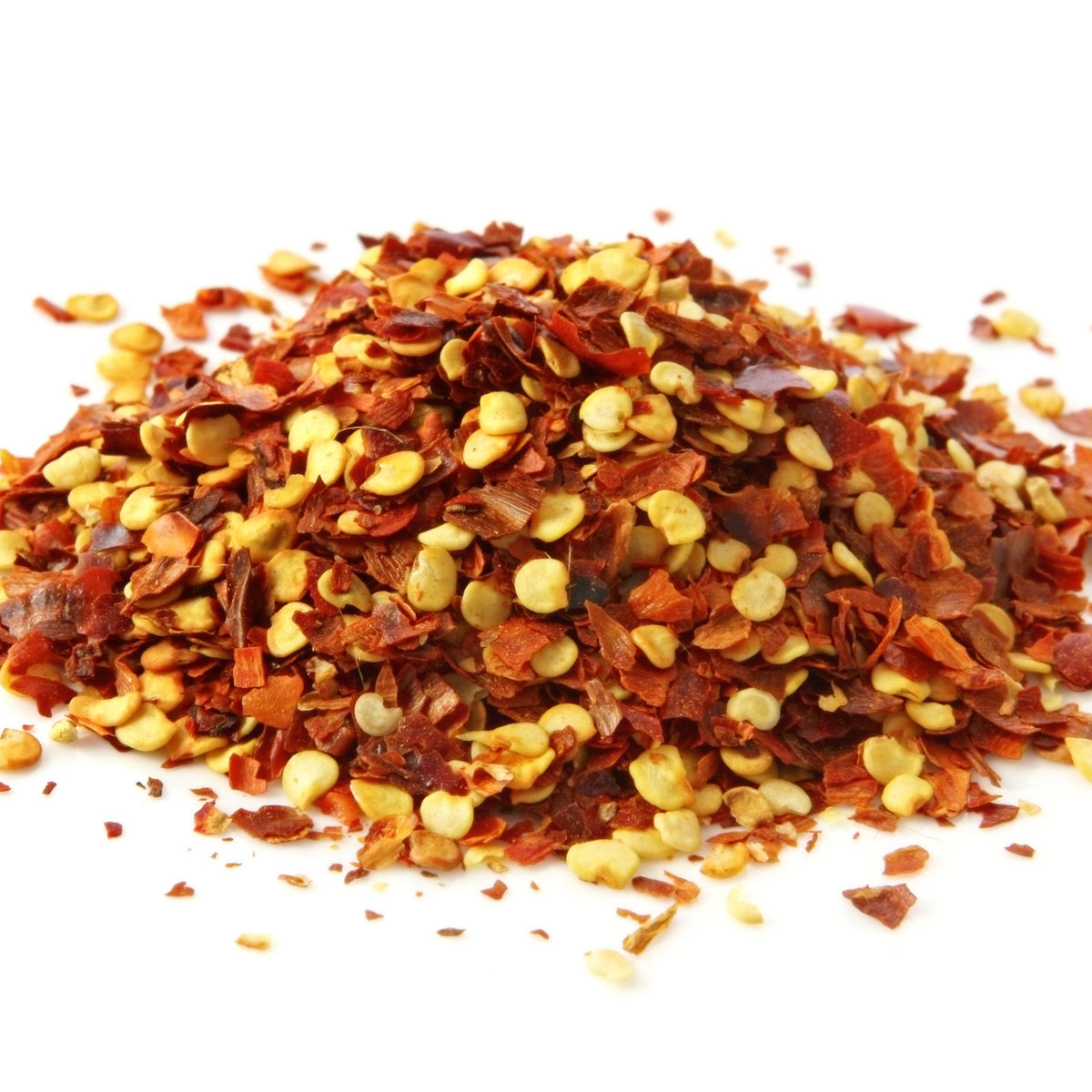 A close-up mound of Organic Chilli Flakes against a white background, showing the crushed red chilli pieces, pale seeds and naturally varied red colouring.