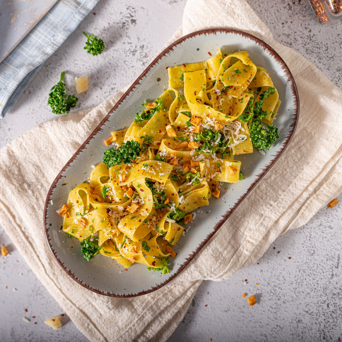 A plate of pasta topped with herbs and Organic Chilli Flakes, showing the flakes used to add heat and flavour to a savoury pasta dish.