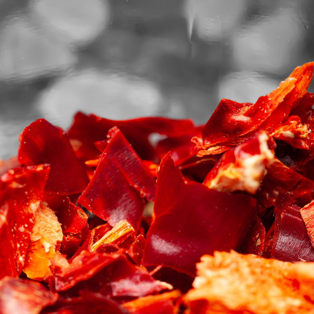 A close-up of Organic Chilli Mild Rough Cut showing the irregular dried red chilli pieces, pale seeds and coarse natural texture.