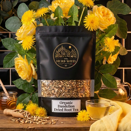 A black stand-up pouch of The Herb Shed Organic Dandelion Dried Root Tea in Wollongong, Australia, sits on a wooden surface with loose dried dandelion root, fresh yellow dandelion flowers and a cup of tea against a black tiled background.