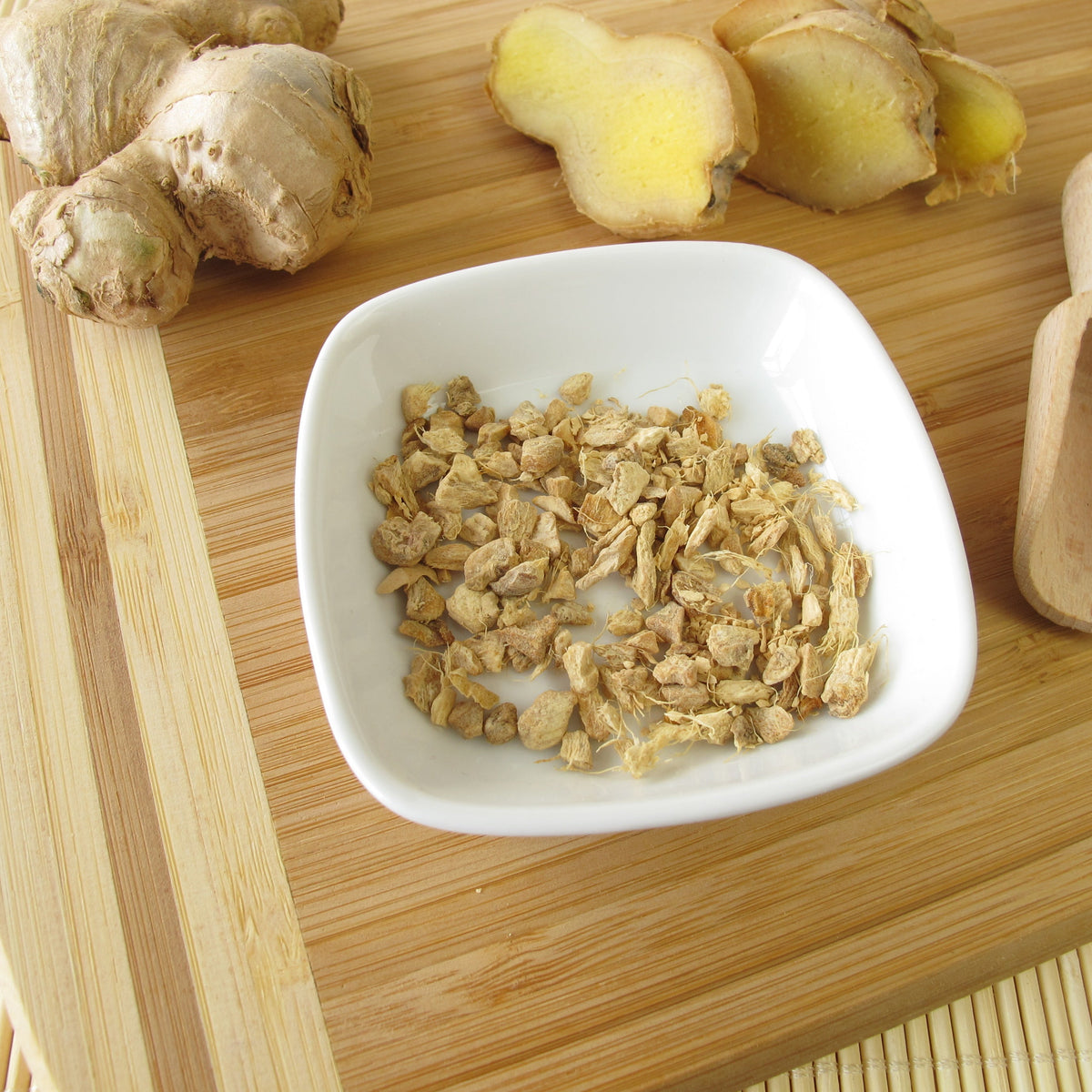Organic Ginger Root Dried from The Herb Shed in Wollongong, Australia, shown in a small dish beside pieces of fresh ginger root.