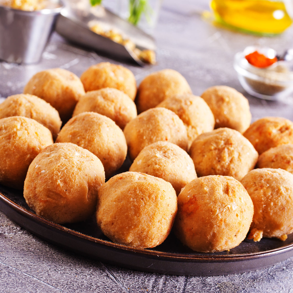 Golden fried savoury bites are arranged on a dark plate, showing Organic Ground Coriander Seed used as part of a seasoned savoury recipe.