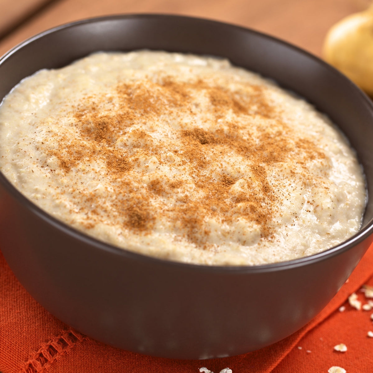 A warm bowl of creamy porridge made with maca powder is topped with a light dusting of spice, showing a breakfast use for The Herb Shed Organic Maca Powder.