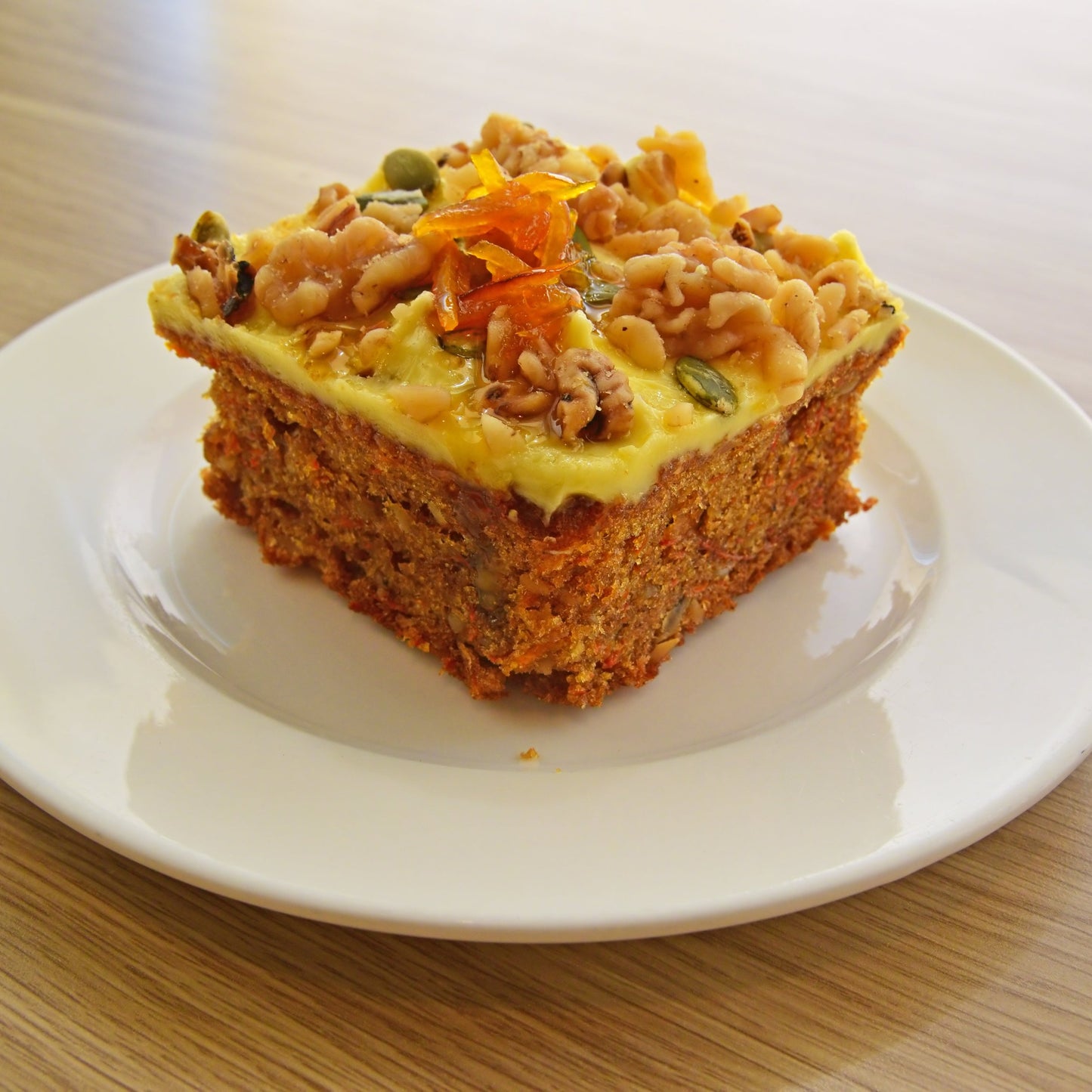 A golden savoury slice topped with pumpkin seeds and herbs is served on a white plate, showing a cooking idea using The Herb Shed Organic Pumpkin Seeds.