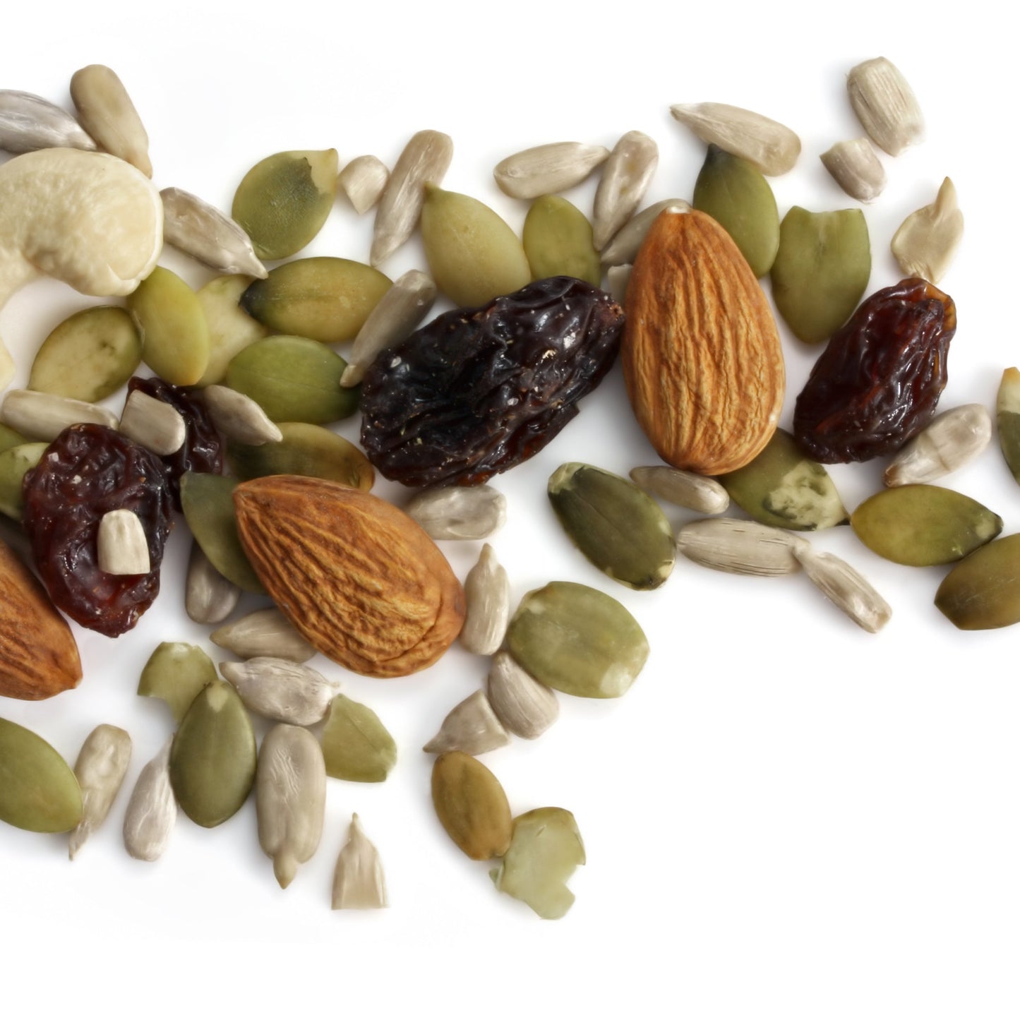 Organic pumpkin seeds are mixed with almonds, cashews and dried fruit on a white surface, showing a trail mix serving idea using pumpkin seeds.