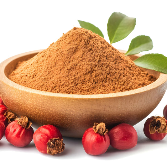 Organic rosehip powder is piled in a wooden bowl surrounded by fresh red rosehips and green leaves, showing the fine texture and warm reddish-brown colour of the powder.