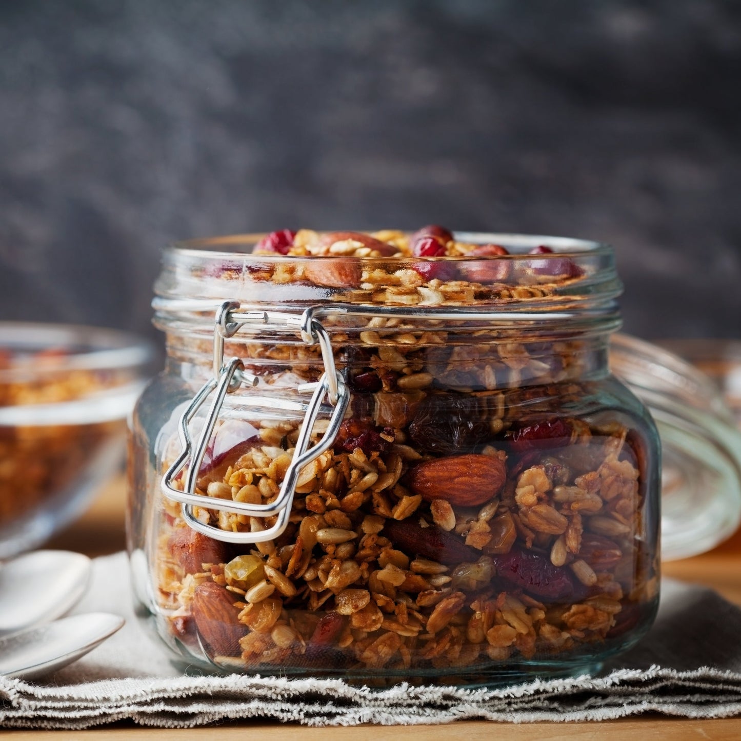 Roasted sunflower seeds fill a small glass jar on a rustic surface, showing their deep golden-brown colour and toasted appearance.