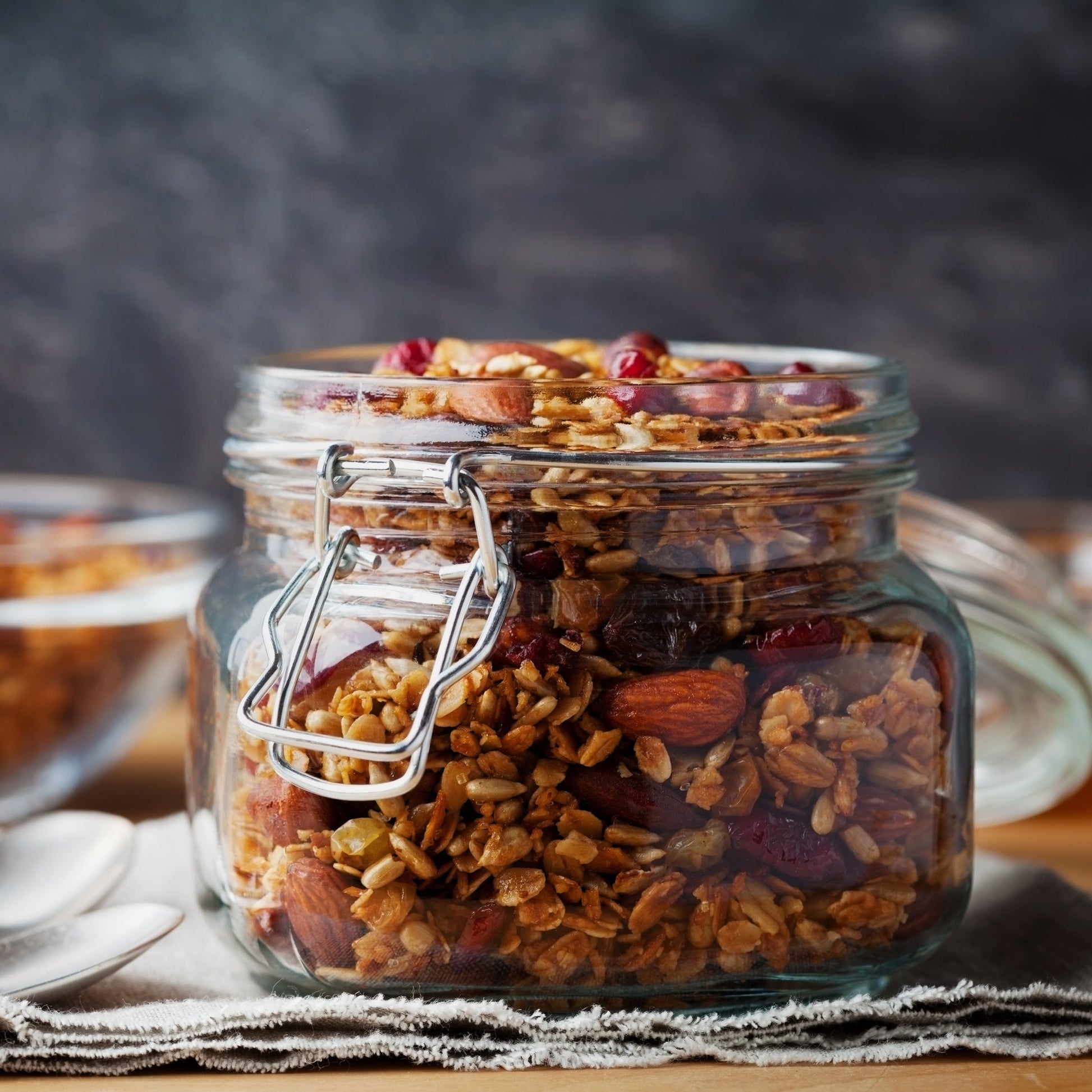 Roasted sunflower seeds fill a small glass jar on a rustic surface, showing their deep golden-brown colour and toasted appearance.