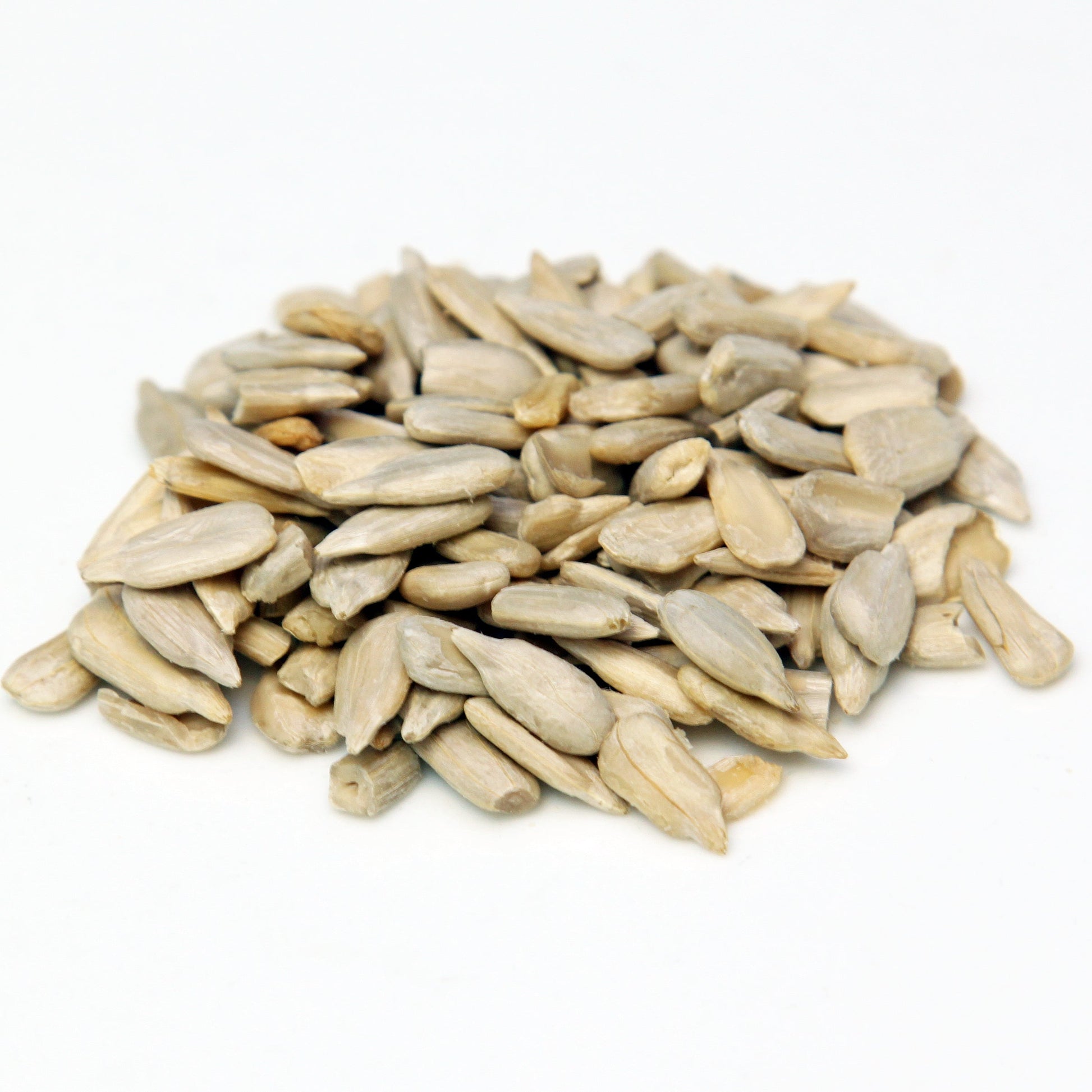 A pile of shelled sunflower seeds sits on a white background, showing the pale cream colour and elongated shape of the kernels.