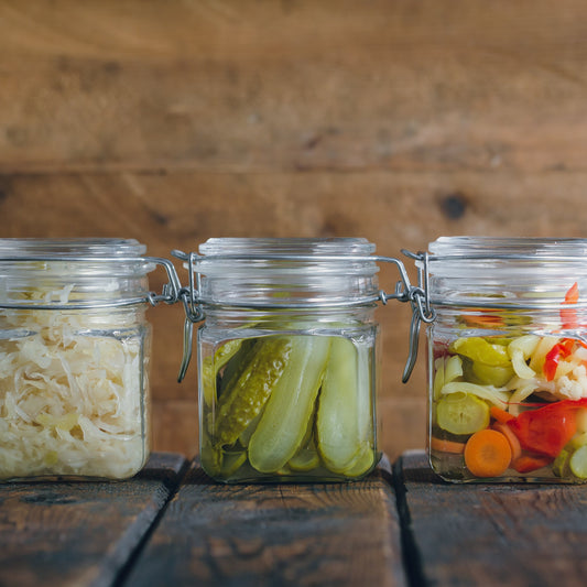 A collection of clip lid glass jars filled with preserved vegetables, showing The Harvest 260ml Jar from The Herb Shed Wollongong used for homemade preserving and pantry storage.