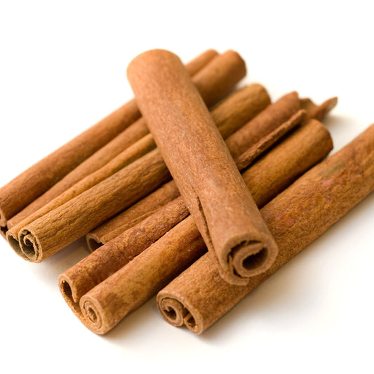 Neatly stacked cinnamon sticks on a clean white background, curled ends and smooth bark clearly visible – The Herb Shed Wollongong