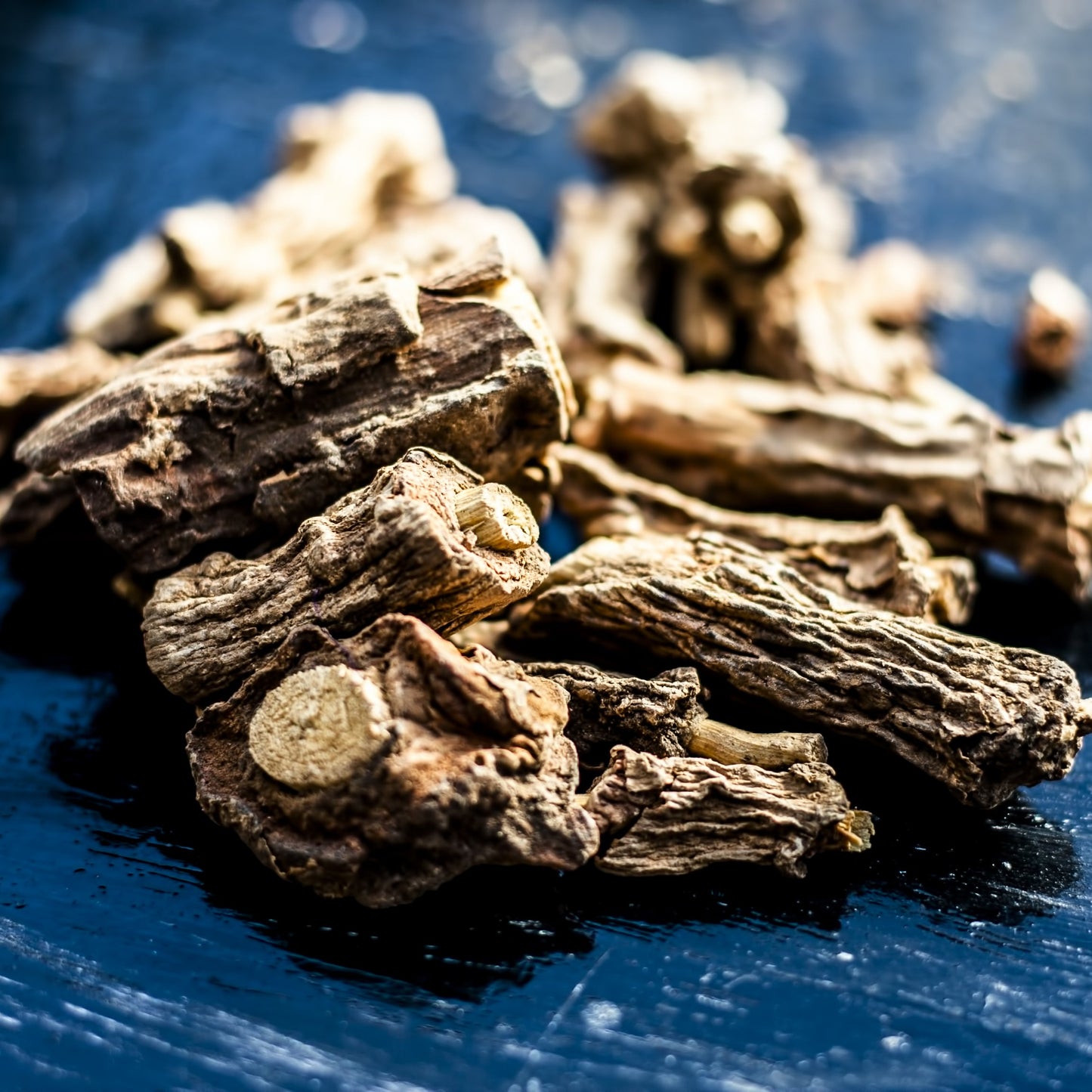 Close-up of whole dried sarsaparilla root pieces on a dark surface – earthy herbal root from The Herb Shed Wollongong